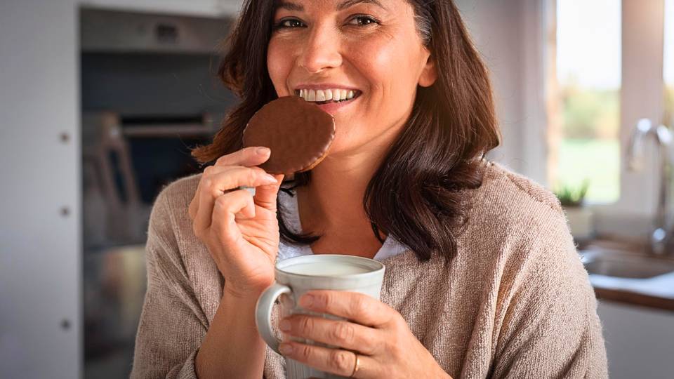 Donna che mangia un biscotto proteico Nuvole ricoperte di cioccolato gusto arancia per dieta chetogenica