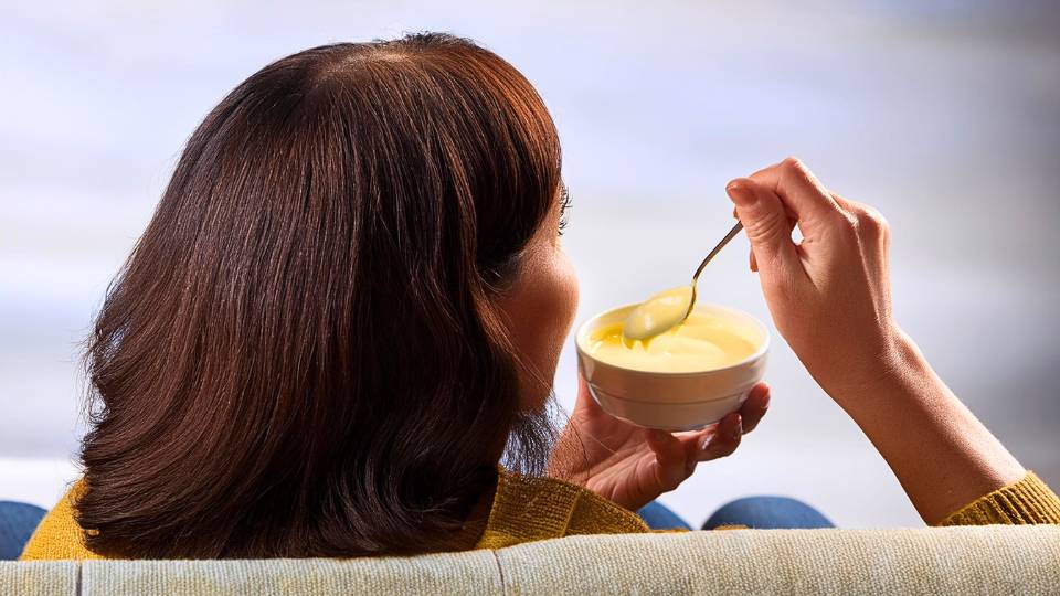 Donna che mangia un budino keto proteico sul divano